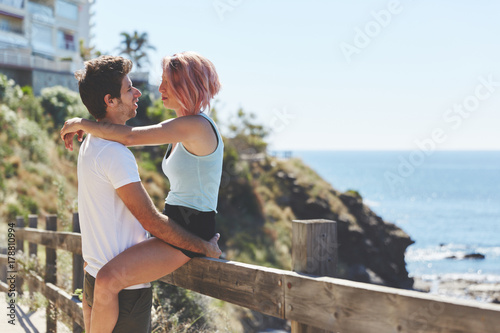Happy woman sitting on fence looking at her boyfriend