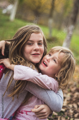 Young sisters hugging and smiling happy in the garden.