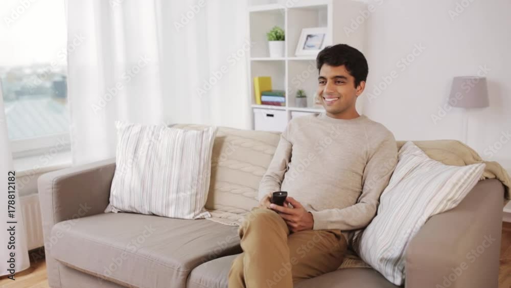 man with remote control watching tv at home man with remote control watching tv at home