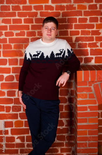 a young man in a New Year's sweater with a deer and New Year's mood