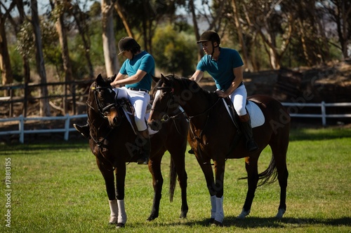 Two male jockeys riding horse