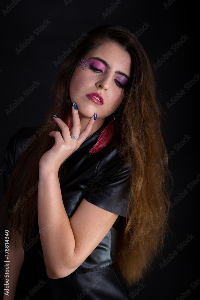 Indoors portrait of attractive young woman with makeup. Half-lenght standing and touching face by hand fingers. Dark background. Indoors portrait of attractive young woman with makeup. Half-lenght standing and touching face by hand fingers. Dark background.