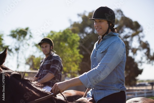 Two male friends riding horse in the ranch