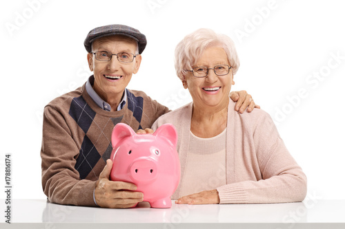 Senior couple with a piggybank seated at a table