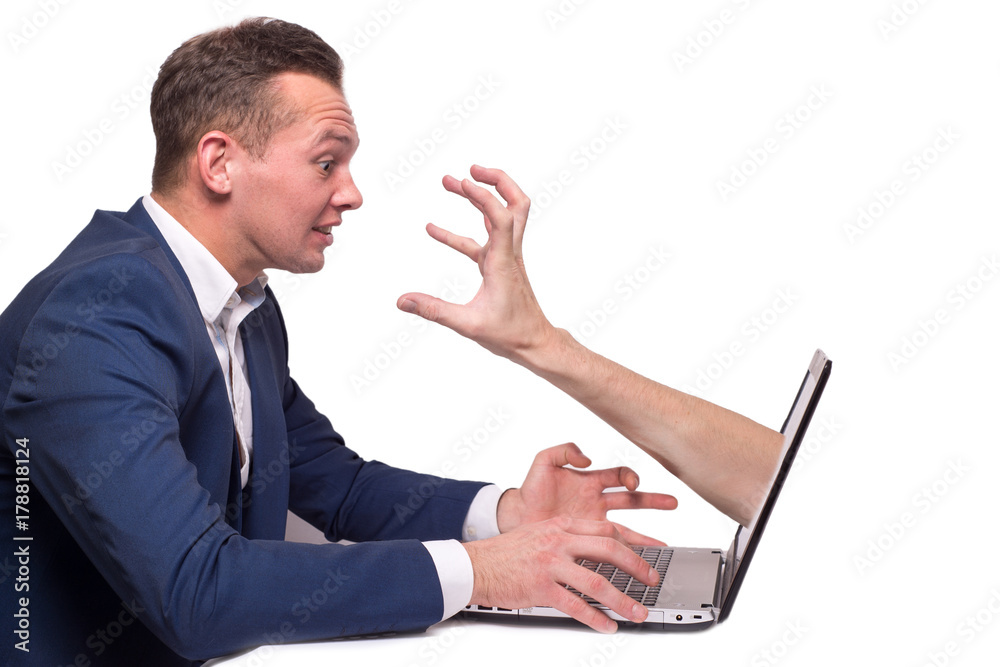 Businessman at the computer with frightened hands .Hand coming out of Laptop screen - symbol for Internet Crime Businessman at the computer with frightened hands .Hand coming out of Laptop screen - symbol for Internet Crime