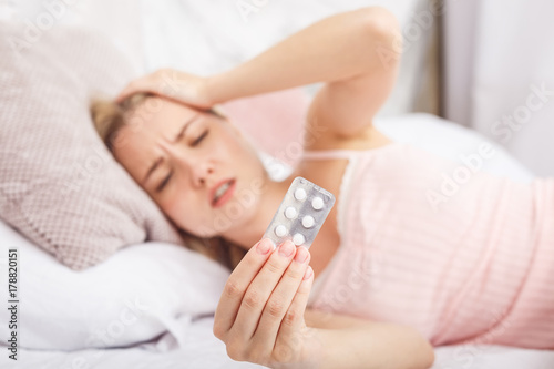 Sick woman lying in bed with high fever. Cold, flu, fever and migraine. In stress. Close-up.