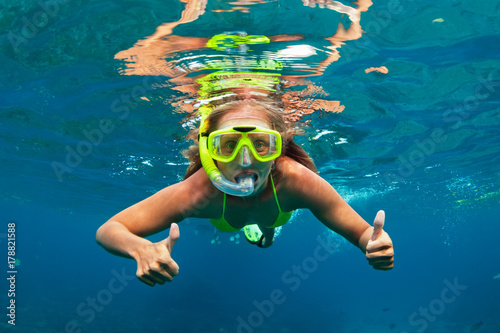 Happy family - girl in snorkeling mask dive with tropical fishes in coral reef sea pool. Travel lifestyle, water sports outdoor adventure, underwater swimming on summer beach holiday with kids.