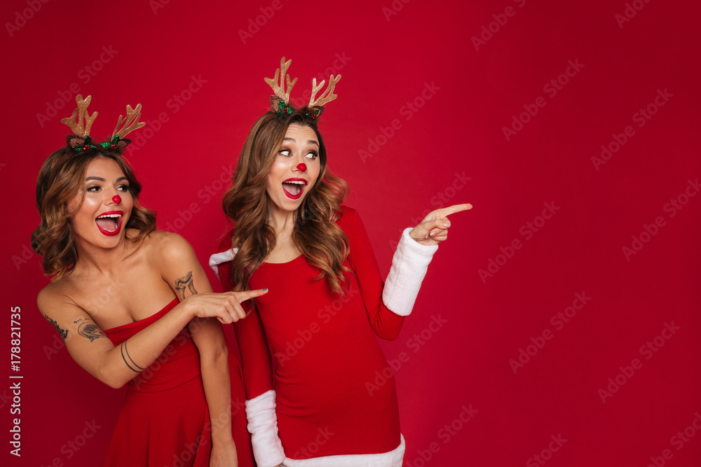 Surprised young women friends wearing christmas deer costumes Surprised young women friends wearing christmas deer costumes
