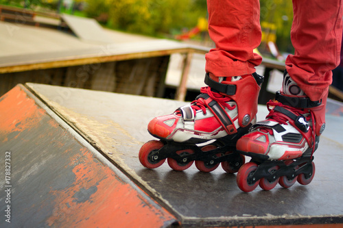 feet in the frame. on rollers in red pants, against the background of the park, doing tricks. © Alex
