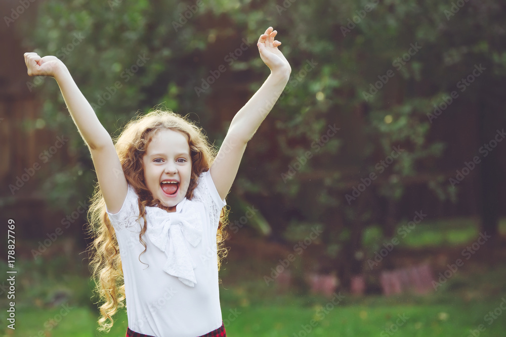 Little girl raised her hands up and screaming hurray in a summer park. Little girl raised her hands up and screaming hurray in a summer park.