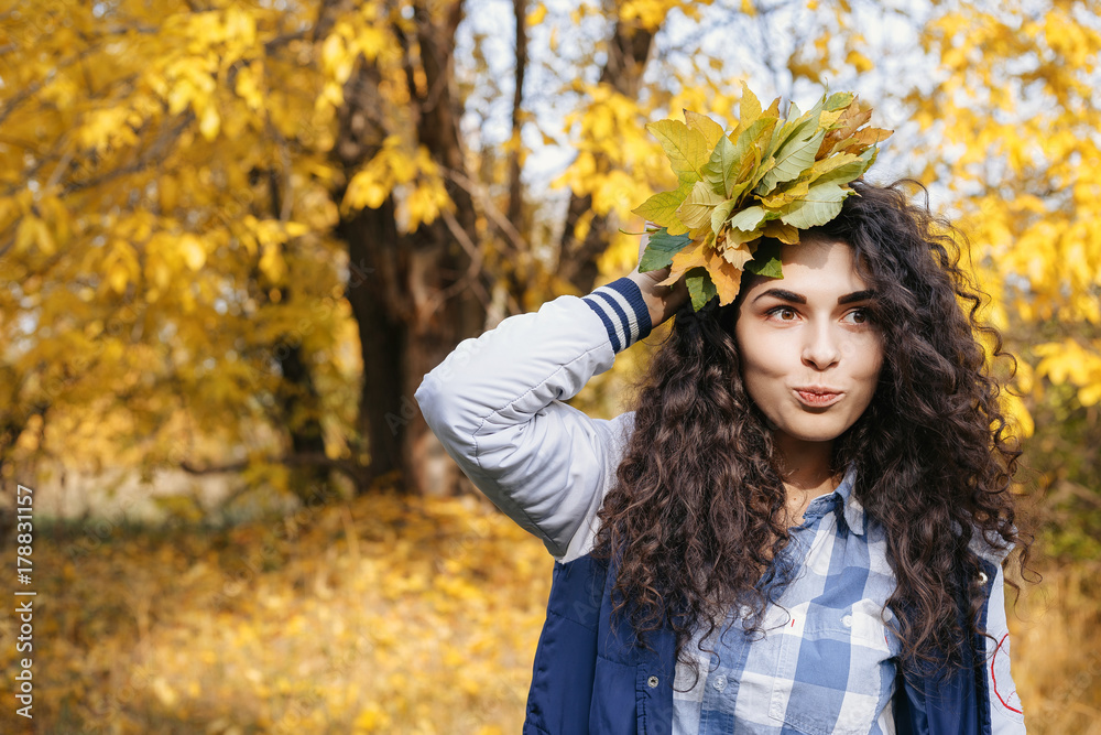 Happy curly woman holding bouquet of autumn leaves in hand and posing in autumn park. Happy curly woman holding bouquet of autumn leaves in hand and posing in autumn park.