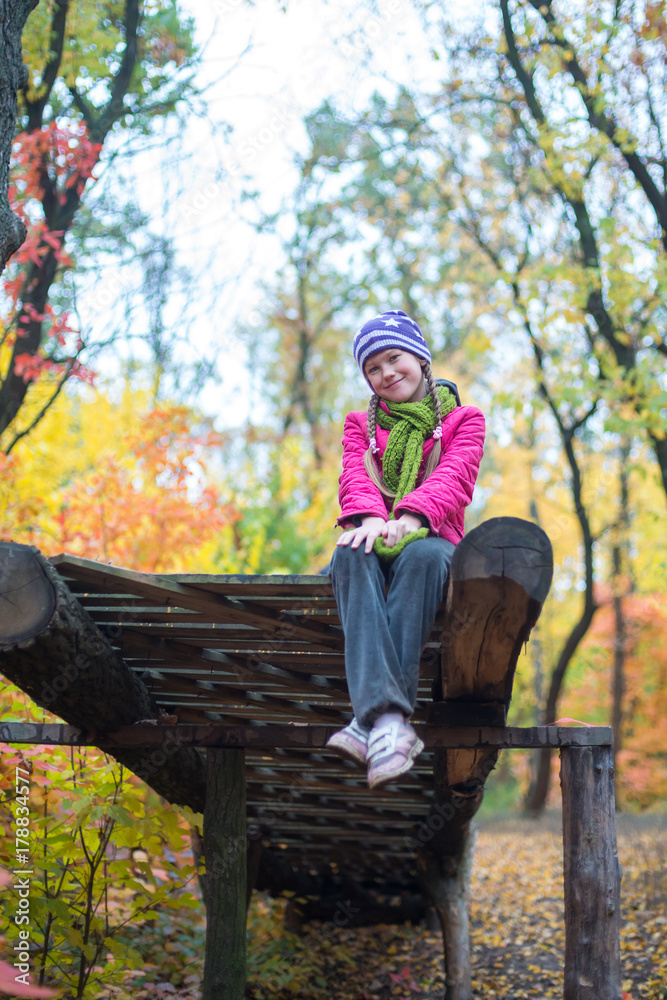 Smiling teenage girl sits in the autumn forest Smiling teenage girl sits in the autumn forest
