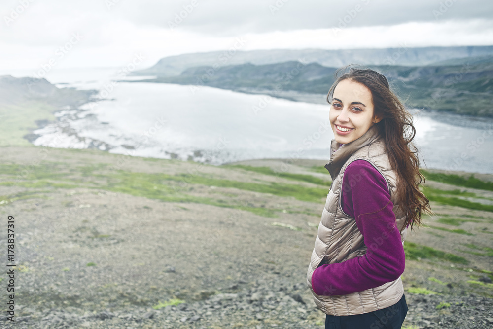 Girl in warm clothing observing surroundings on background of mountains and sea of Iceland. Girl in warm clothing observing surroundings on background of mountains and sea of Iceland.