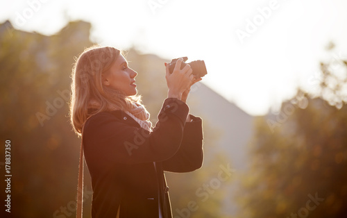 Girl taking picture with camera during sunset in the city