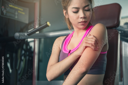 Young woman with elbow pain in gym. A woman having pain in injured elbow after workout.