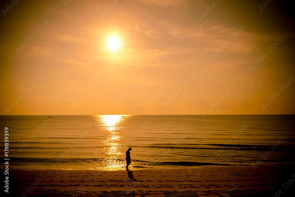 Golden sun set in tropical hot summer beach in thailand with unidentified person in background,