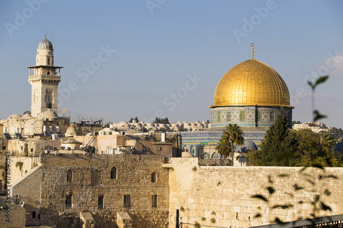 Old city quarter of ancient Jerusalem with light brown stone walls of houses, high tower and dome of the mosque