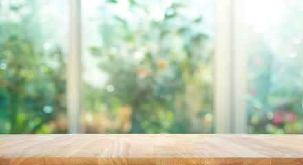 Wood table top on blur of window with garden flower background in morning.For montage product display or key visual layout.