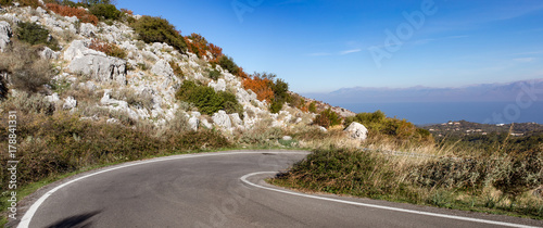 The road down from the highest mount (Pantocrator) on the Ionian Island Corfu, Greece. Rocks, beautiful  autumn colors, blue sky.