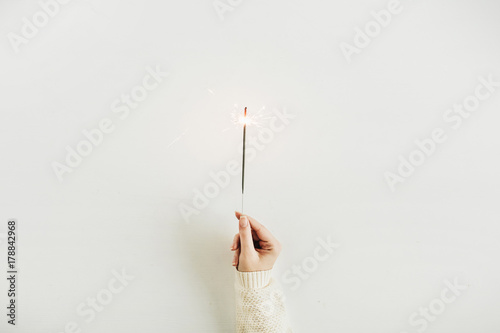 Holiday concept. Woman hand holding bengal light. Christmas flat lay, top view.