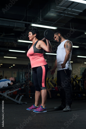 Male personal trainer assisting his client in gym
