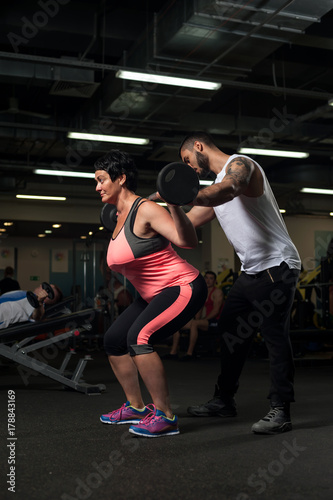 Male personal trainer assisting his client in gym
