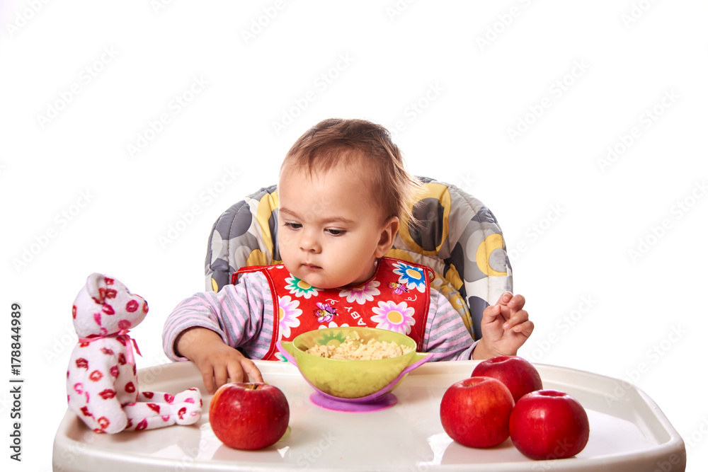 little child eats with spoon sitting at table with fruits isolated little child eats with spoon sitting at table with fruits isolated