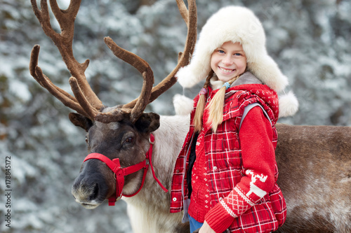 Winter playtime.Happy little girl hugging her reindeer.
