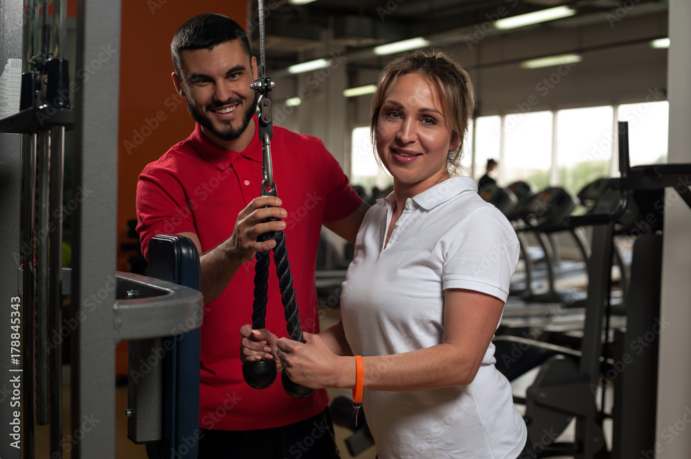 Cheerful woman working out in gym with coach Cheerful woman working out in gym with coach
