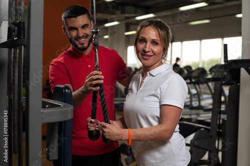 Cheerful woman working out in gym with coach
