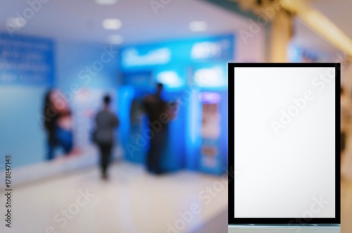 vertical advertising billboard or blank showcase light box for your text message or media content with blurred image of people queuing to withdraw money from ATM banking machine, commercial concept