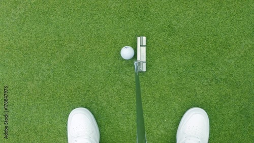Close-up of golfer using putter to sink short putt into hole