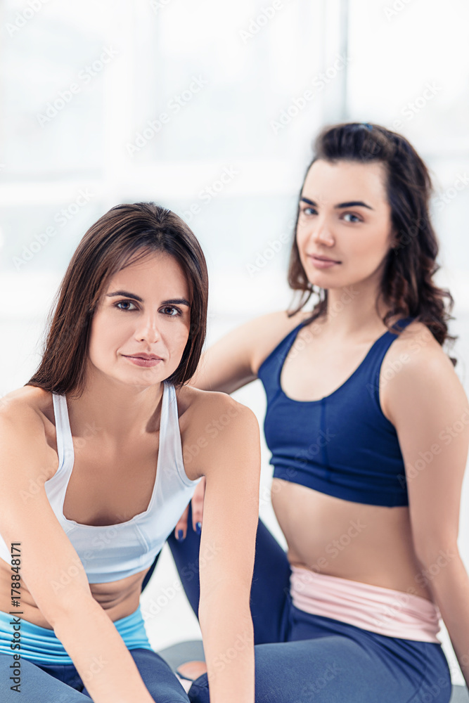 Two young sporty women posing at gym.