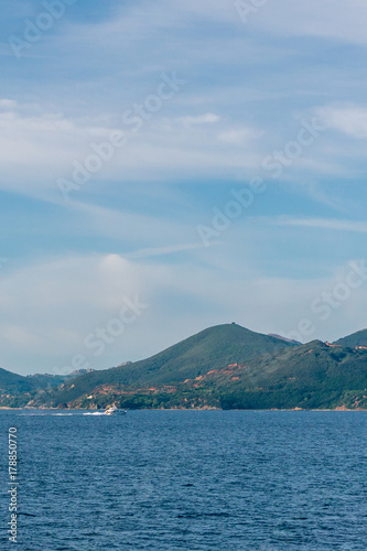 A boat on the sea with Tuscany mountains in background