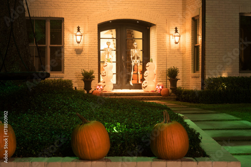 The house is decorated for Halloween: pumpkins are real and artificial, skeletons on the doors. Night photo