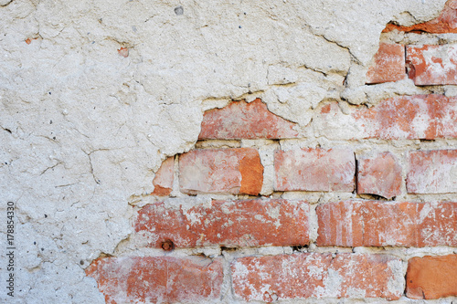 The wall of the old brick is partially covered with plaster