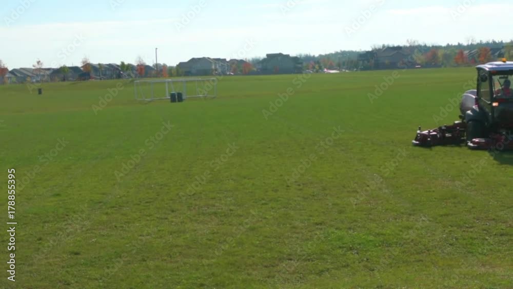 Lawn tractor mowing grass on a football field Lawn tractor mowing grass on a football field