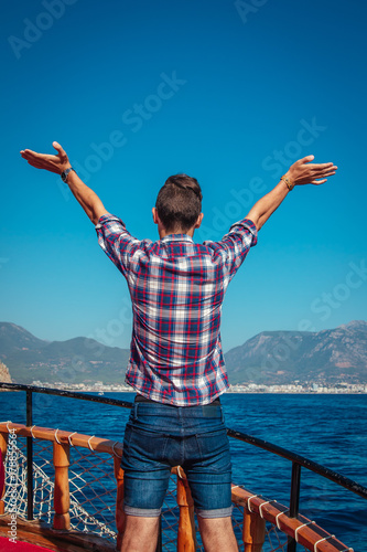 Young man enjoys the seaside view on a wooden yacht