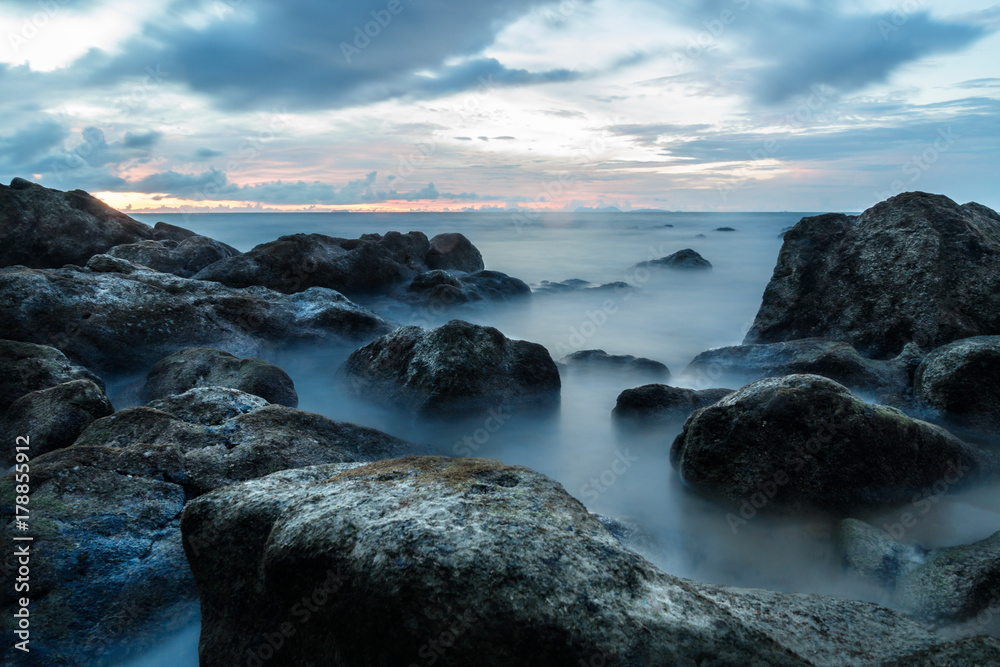 Obraz premium Smooth ocean as long exposure during sunset at Koh Lanta with Stones in the sea and Phi Phi islands in the horizon, Koh Lanta, Thailand, Asia