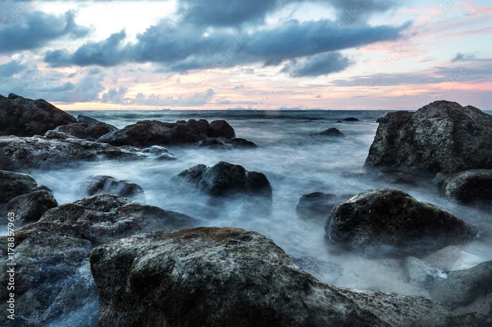 Waves in long exposure in the ocean at sunset at Koh Lanta with Stones in the sea and Phi Phi islands in the horizon, Koh Lanta, Thailand, Asia