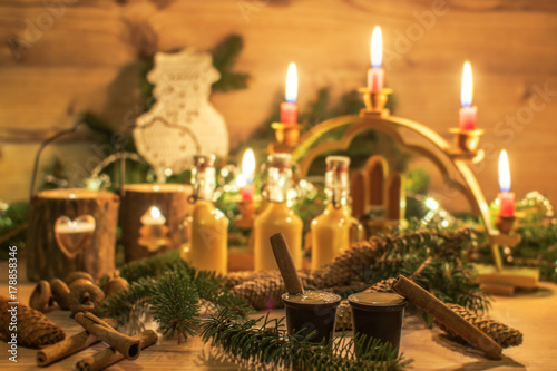 Traditional eggnog with cinnamon sticks in chocolate cup. Christmas decoration and ornaments on wood background. Festive Christmas alcoholic drink, cocktail in an atmospheric environment