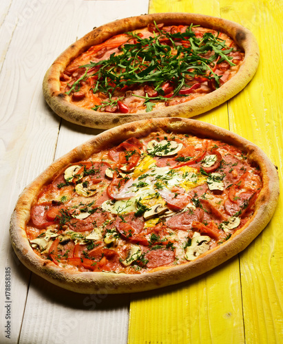 Pizza with pepperoni, mushrooms and egg on yellow wooden background photo