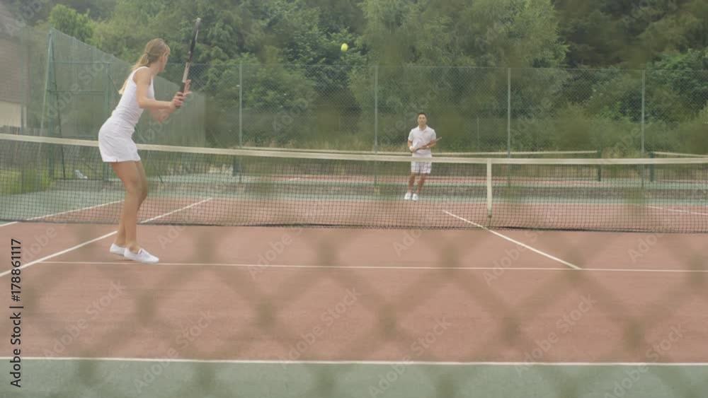Male & female tennis players enjoying a game on outdoor court in the summer Male & female tennis players enjoying a game on outdoor court in the summer