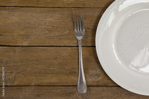 White plate and fork on wooden table