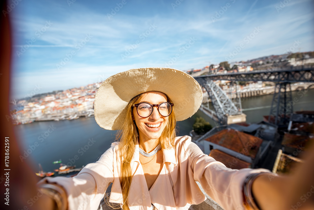 Young woman tourist making selfie photo on the beautiful cityscape background during the morning light in Porto city, Portugal