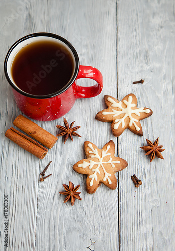 Red cup of tea and two snowflakes Christmas cookies on the grey wooden table