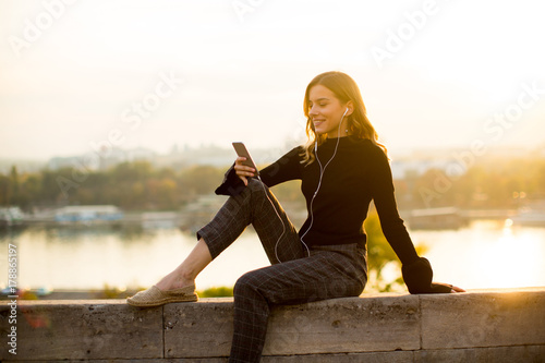 Trendy young woman listenin...
