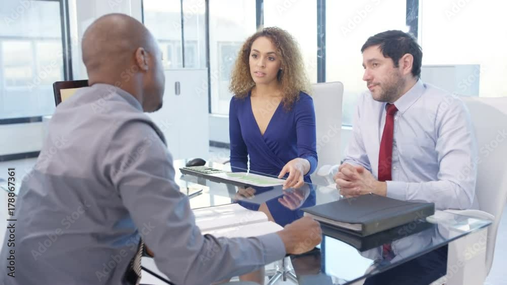 Corporate business team in a meeting looking at paperwork with financial data Corporate business team in a meeting looking at paperwork with financial data