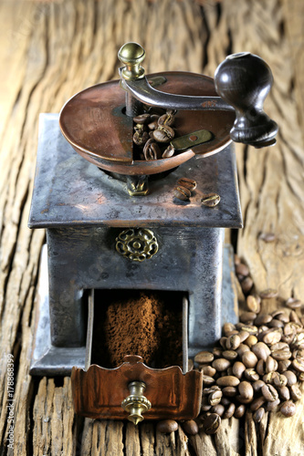 vintage coffee grinder with manufacture roasted Indonesian Arabica coffee beans on rustic wooden background