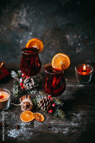 christmas hot mulled wine with spices, candle and traditional New Year decorations and orange on wooden background